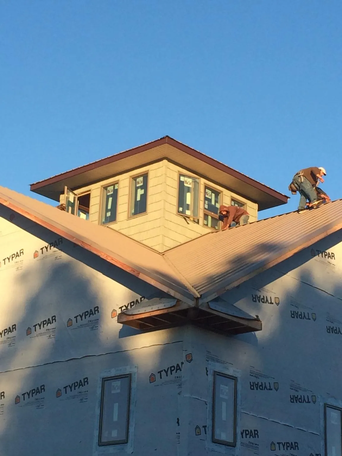 Roofers working around a rooftop cupola on a new metal roof at sunset — Roof Waterproofing in Walworth by Roofing Brothers